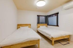 two twin beds in a room with a window at ドリームホテル大博 in Fukuoka