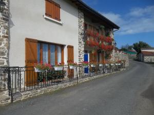 una casa con flores en las ventanas y una valla en Au bon Accueil anciennement Le Jardin fleuri, en Bonnac