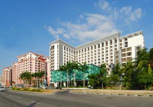 ein großes weißes Gebäude in einer Stadtstraße mit Palmen in der Unterkunft Promenade Hotel Kota Kinabalu in Kota Kinabalu