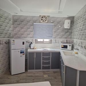 a kitchen with a white refrigerator and a clock on the wall at كوخ ريفي تنومة in Tanomah +48 photos