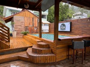 a wooden deck with a pool and a bar at Pousada Recanto do Canário 2 in Governador Celso Ramos