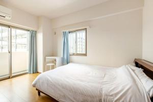 a bedroom with a white bed with blue curtains at Jintai House501 in Fukuoka