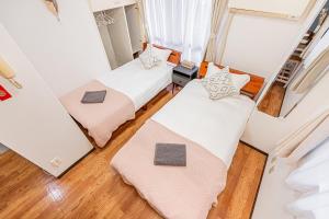 twee bedden in een kleine kamer met houten vloeren bij 新宿区歌舞伎町伊势丹徒步3分钟#6 in Tokyo