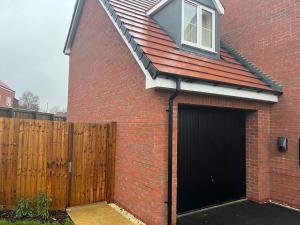 een rood bakstenen huis met een garage met een raam bij Cozie Zone & Brekkie Hucknall, Nottingham in Hucknall
