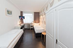 アーヘンにあるホテル クローネ アーヘン シティ ユーログレスのベッド2台とデスクが備わるホテルルームです。