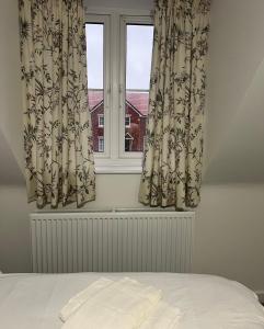 een slaapkamer met een raam met gordijnen en een bed bij Cozie Zone & Brekkie Hucknall, Nottingham in Hucknall