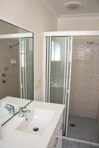 Un baño blanco con lavabo y ducha. en Baybreeze - Bring your own linen, en South West Rocks