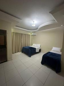 a room with two beds and a flat screen tv at Linda casa a 200m da Basílica Nova in Aparecida