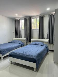 a bedroom with two beds and two windows at Nongnuchs Homestay Two Single Beds in San Sai