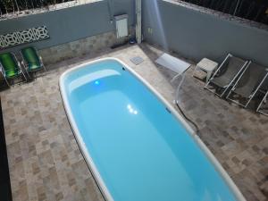 a large swimming pool in a bathroom with chairs at Pousada do sossego mar e verde 1,2 e 3 in Itanhaém