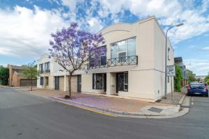 a white building with a purple tree in front of it at 2BR Urban Nest Cosy & Central - Free Parking in Adelaide +24 photos