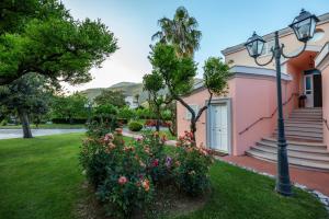 a pink house with a light pole and flowers at Villa Irlanda Grand Hotel in Gaeta
