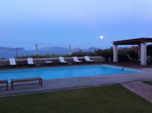 a swimming pool with chairs and a gazebo at Xenon Estate in Spetses