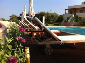 a row of lounge chairs sitting next to a swimming pool at Xenon Estate in Spetses