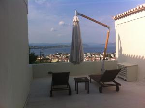 a balcony with two chairs and an umbrella at Xenon Estate in Spetses