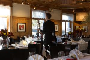 a man standing in a dining room with tables at Hotel Landhaus Säntis Herisau in Herisau