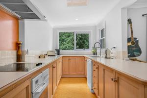 奥兰治Meadowbrook MTB Lodge Orange - Rip on the trails, sip on the wine!的厨房配有木制橱柜和墙上的吉他