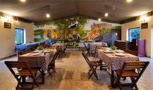 a restaurant with tables and chairs and a mural at Jungle Book Resort Ranthambore camping Near Tiger safari in Sawāi Mādhopur