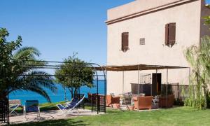 a patio with chairs and an umbrella and the ocean at Maragani Beach in Maragani