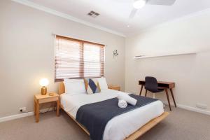 ein Schlafzimmer mit Bett, Schreibtisch und Fenster in der Unterkunft Directors Cottage Fabulous Local & Peaceful in Fremantle