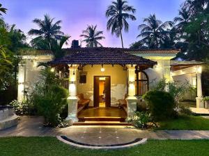 a house with a front porch with palm trees at Casa Maya - 2 Bedroom Portuguese Villa with Private Pool in Candolim