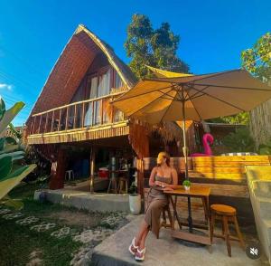 a woman sitting at a table under an umbrella at GAïA Cabinhouse in Cebu City
