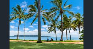 twee mensen zitten onder palmbomen op het strand bij Waters Edge The Strand in Townsville