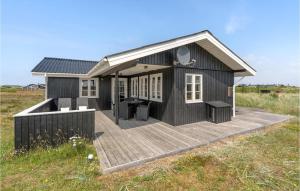 a black house with a deck in a field at Holiday Home Arvidvej Hvide Sande Xii in Bjerregård +17 photos