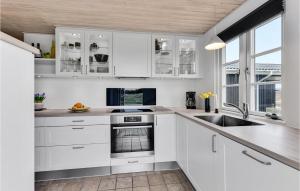 a white kitchen with white cabinets and a sink at Holiday Home Arvidvej Hvide Sande Xii in Bjerregård