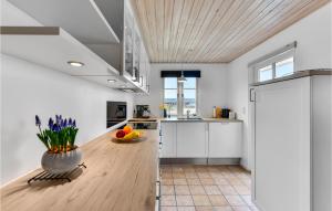 a kitchen with white cabinets and a vase of flowers at Holiday Home Arvidvej Hvide Sande Xii in Bjerregård