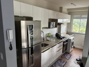 une cuisine avec des armoires blanches et un réfrigérateur en acier inoxydable dans l'établissement Apartamento Vagner, à Balneário Camboriú