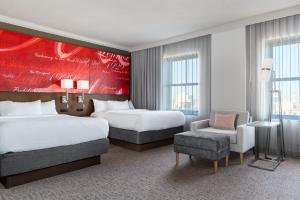 a hotel room with two beds and a chair at Courtyard St. Louis Downtown/Convention Center in Saint Louis +36 photos