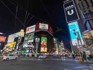 a busy city street at night with a lot of signs at Tabist THE GREEN SAPPORO in Sapporo