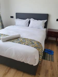 a bedroom with a large bed with white sheets at The Heart of Urban in Nairobi