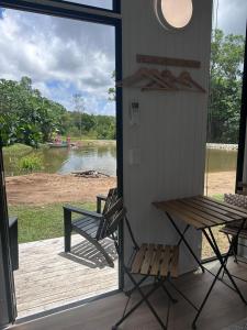 a porch with a bench and a view of a lake at The Dacious by Tiny Away in Midgenoo +2 photos