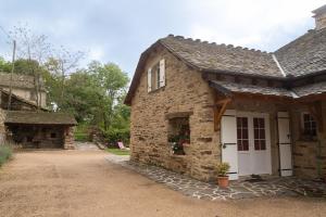 a stone house with a white door and a driveway at Gîte a les rosiers in Chadenet