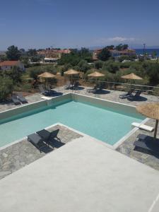 a swimming pool with chairs and umbrellas at Rachoni Amazing Rooms and Maisonettes in Skala Rachoniou
