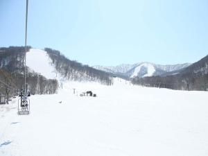 a snow covered ski slope with a ski lift at Urabandai Cranes in Kitashiobara