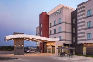 a hotel with tables and umbrellas outside of it at Fairfield by Marriott Inn & Suites Omaha at MH Landing in Omaha