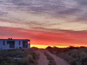 a house on a dirt road with a sunset at The Daiquiri Shaq in St Helena Bay