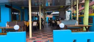 un ristorante con tavoli e sedie in legno e pareti blu di Tiny Temple a Varkala