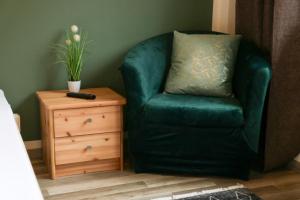 a green chair with a pillow next to a dresser at Kreilingshöfchen Apartments in Bad Vilbel
