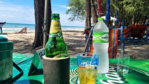two bottles of beer sitting on a table at the beach at Apartment with wonderful view, Mae Ramphueng Beach, Rayong in Rayong