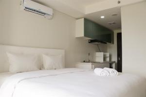 Un dormitorio con una cama blanca con toallas. en Elegant and Comfy Studio at Daan Mogot City Apartment By Travelio, en Yakarta