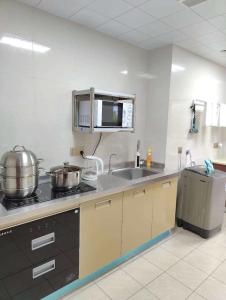 a kitchen with two pots and a sink and a microwave at Kaibu Courtyard Superior Apartment, Changjiang Cable Car Nanbin Road, Chongqing in Chongqing