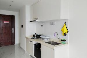 biała kuchnia ze zlewem i kuchenką w obiekcie Elegant and Strategic 2BR Sky House BSD Apartment By Travelio w mieście Tangerang