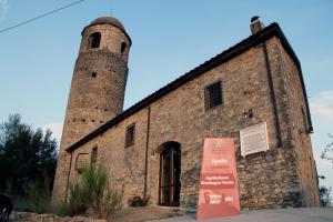 an old brick building with a tower with a sign in front at Agriturismo Montagna Verde Apella in Licciana Nardi