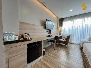 een hotelkamer met een bureau en een bed bij Slive Hotel in Surin