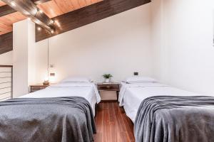 two beds in a room with white walls and wooden ceilings at [Chardonnay]- elegante appartamento in Cavezzo