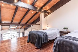 two beds in a room with wooden ceilings and wood floors at [Chardonnay]- elegante appartamento in Cavezzo